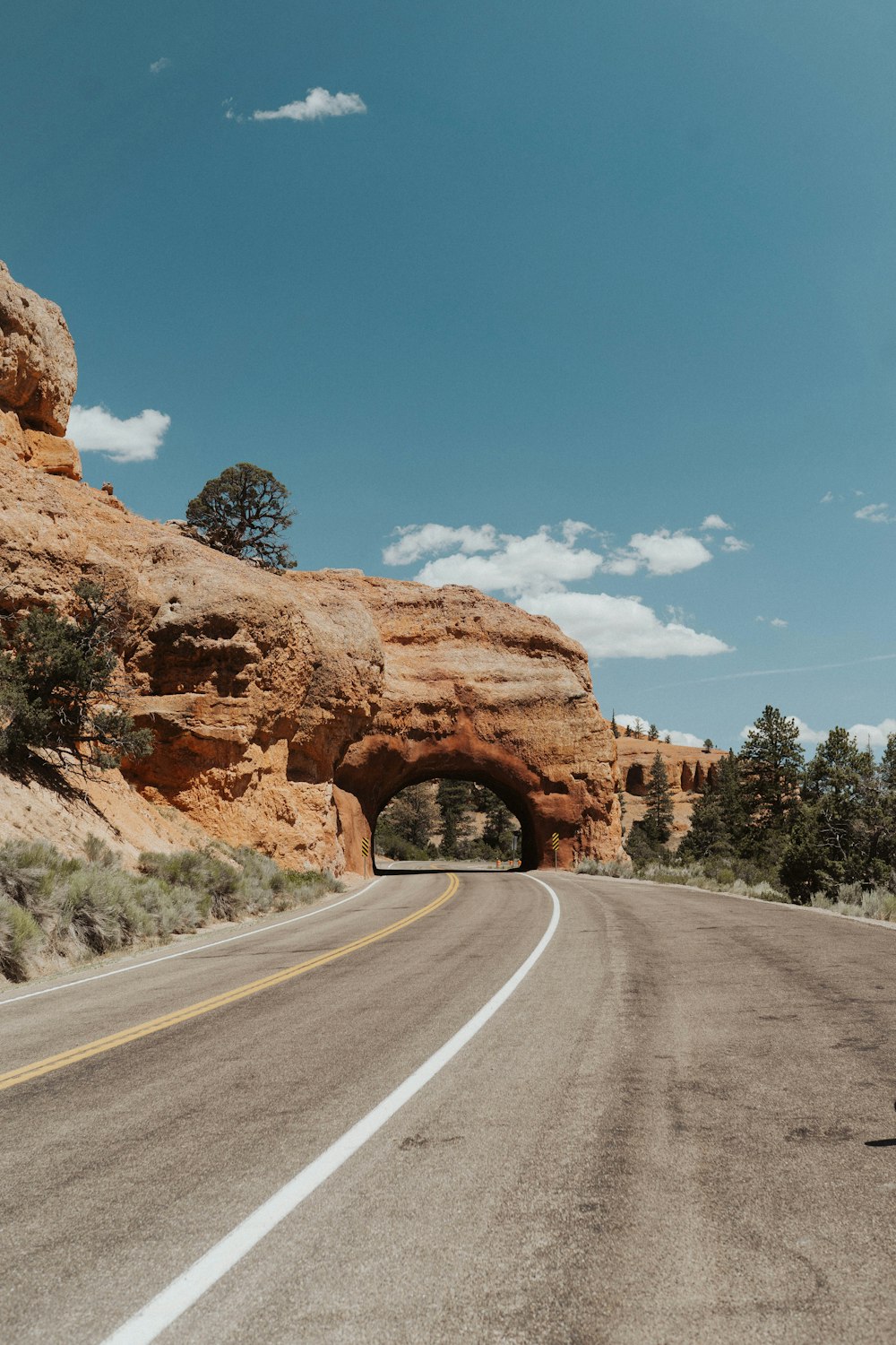 brown rock formation near gray asphalt road under blue sky during daytime