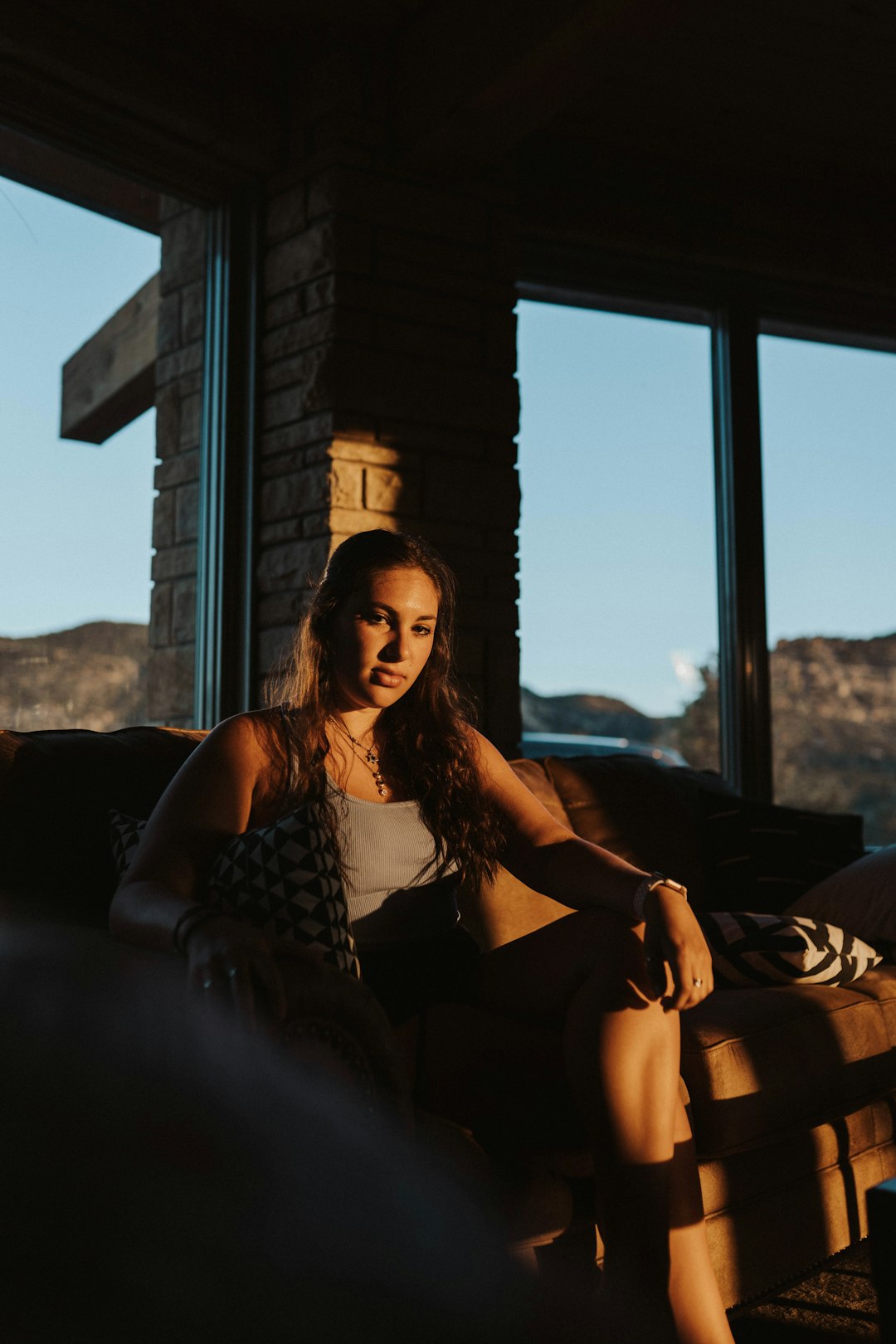 woman in black and white sleeveless dress sitting on brown couch