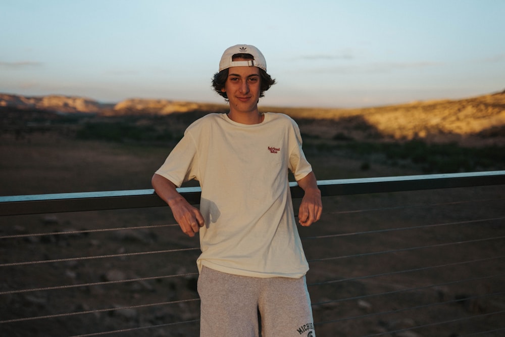 man in gray crew neck t-shirt and brown cargo pants standing on brown wooden bridge