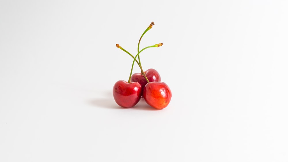 3 red cherries on white surface