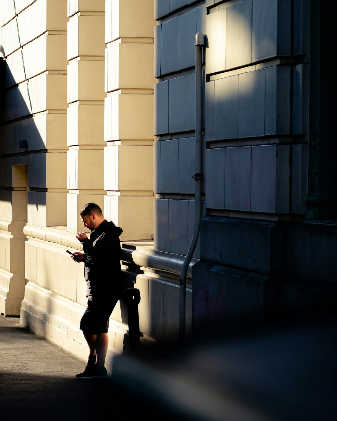 woman in black jacket and black pants sitting on white concrete wall during daytime