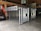 A metal storage or transport crate with a diamond plate pattern is situated in a garage. The crate is constructed from aluminum, featuring a sturdy frame with a grid-like design and handles on the sides.