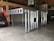 A metal storage or transport crate with a diamond plate pattern is situated in a garage. The crate is constructed from aluminum, featuring a sturdy frame with a grid-like design and handles on the sides.
