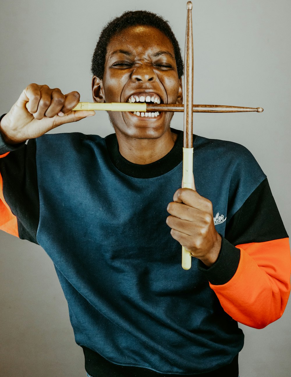 man in blue sweater holding brown wooden stick