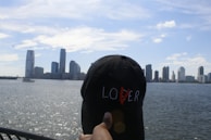 Close-up of hands adjusting a Concrete Soul snapback hat with city skyline in background