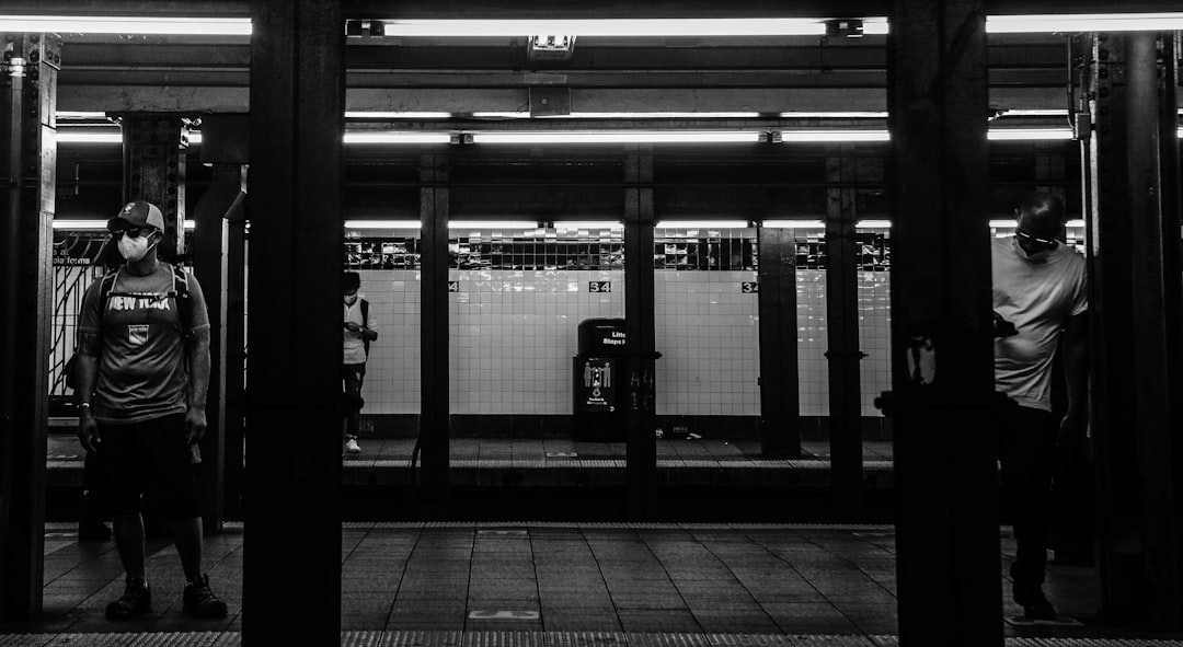 grayscale photo of people walking on train station