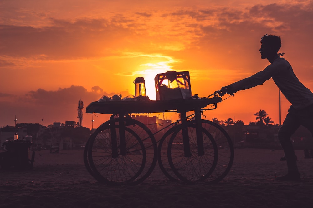 Silueta de la bicicleta en la playa durante la puesta del sol