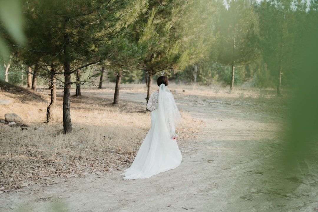 woman in white wedding dress walking on dirt road during daytime