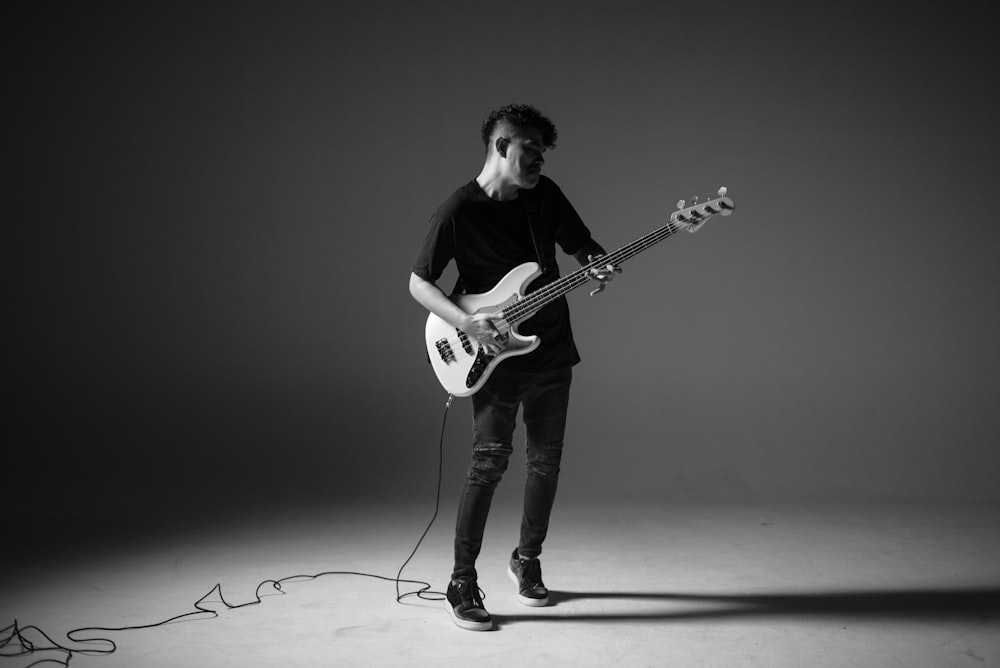 man playing guitar in grayscale photography