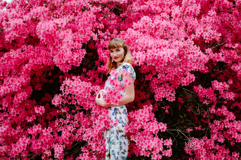 woman in white and pink floral dress standing beside pink flowers