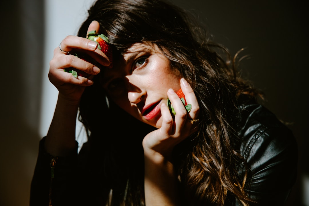 woman in black tank top holding her face