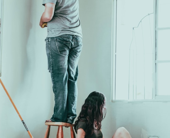 woman in gray t-shirt and blue denim jeans sitting on brown wooden seat