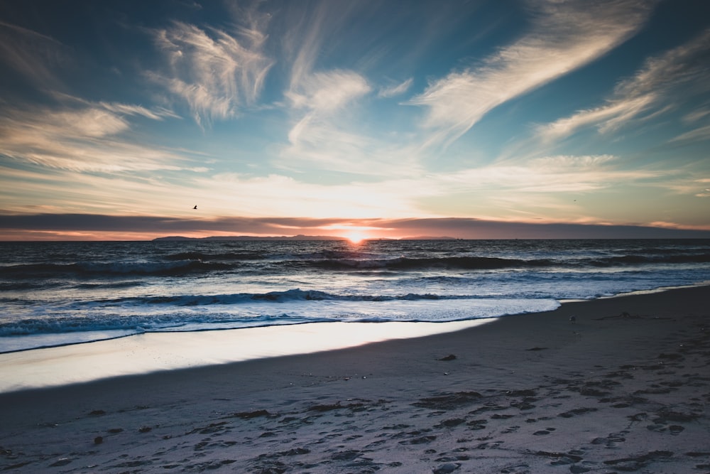 sea waves crashing on shore during sunset