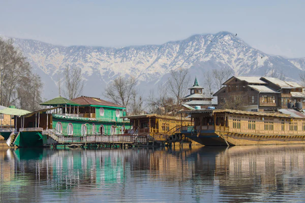 Carved wooden houseboats moored on a still lake below snow-dusted mountains