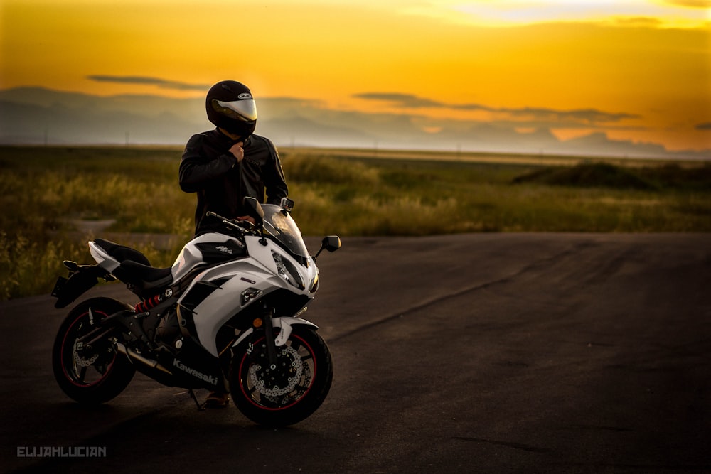 man in black jacket riding white sports bike on road during daytime