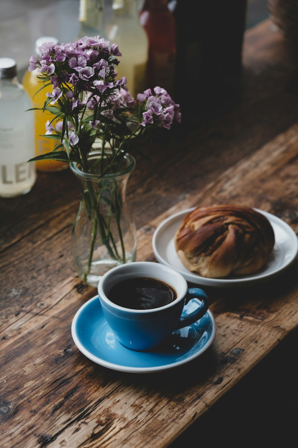 blue ceramic cup with saucer beside flower vase