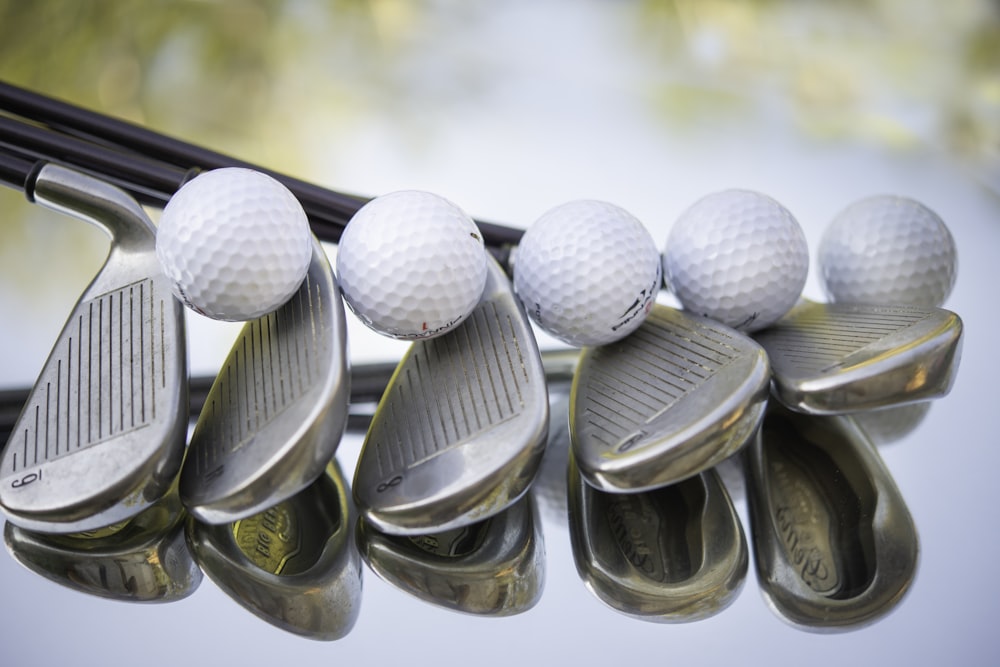 um grupo de bolas de golfe e ferros pendurados em um rack