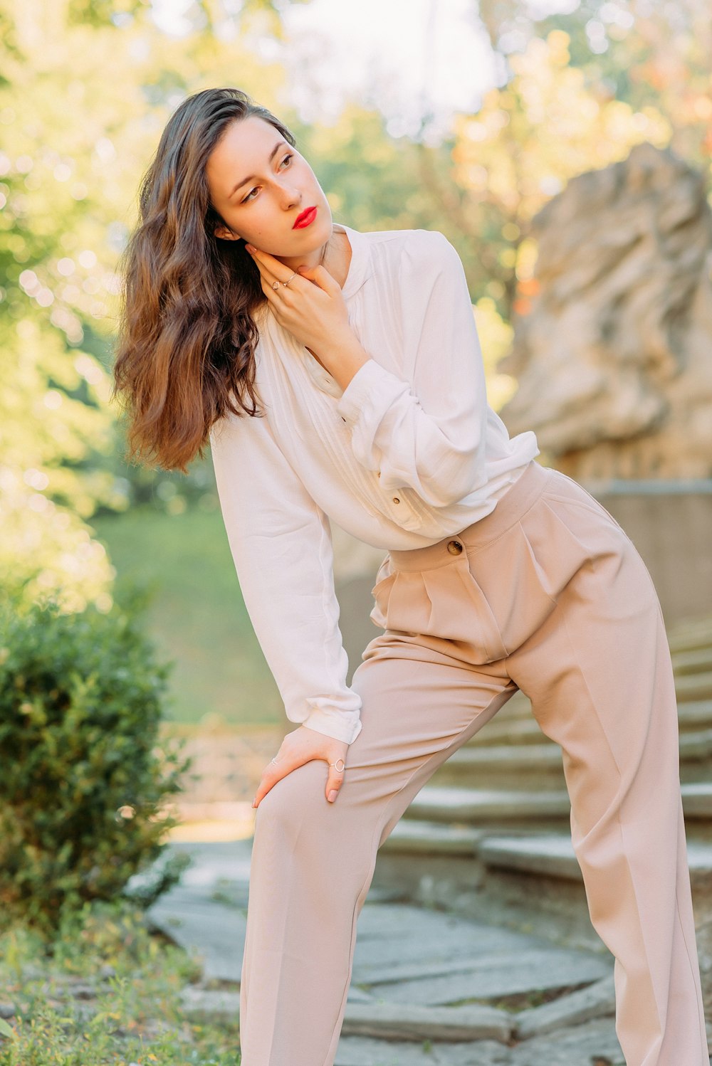 woman in white long sleeve shirt and beige pants sitting on brown wooden bench during daytime