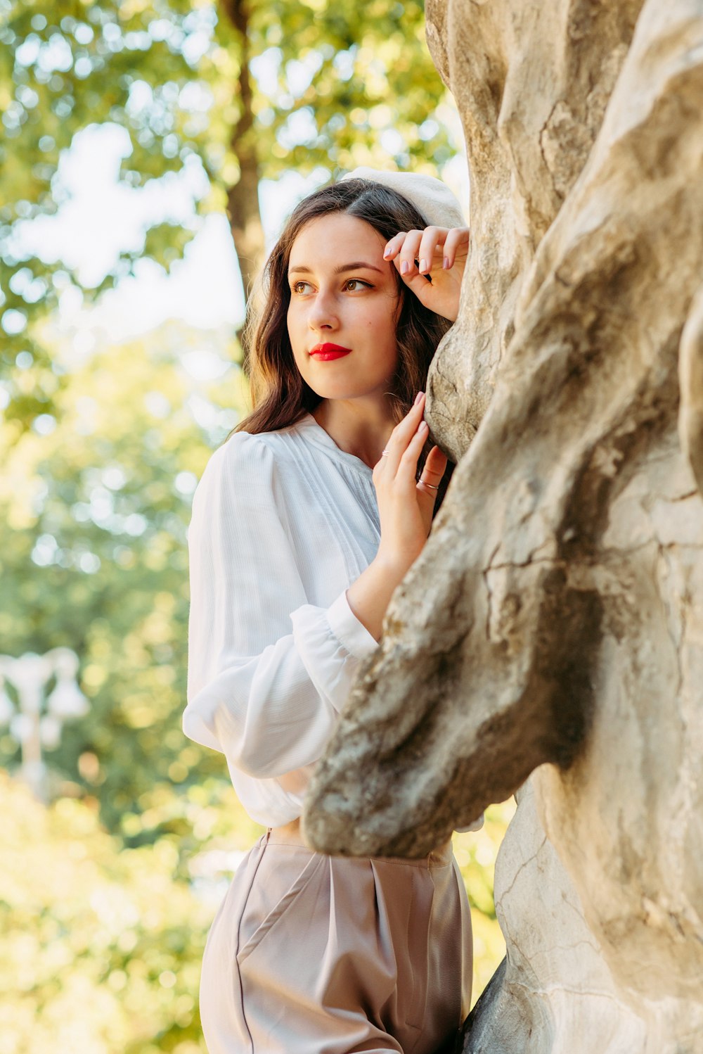 woman in white long sleeve shirt leaning on brown rock during daytime