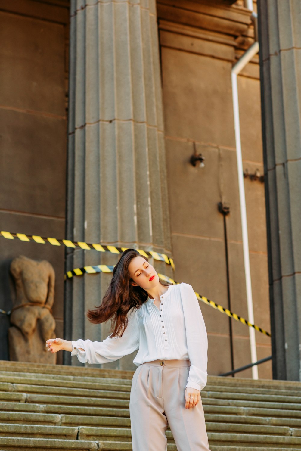 woman in white long sleeve shirt standing beside brown building during daytime