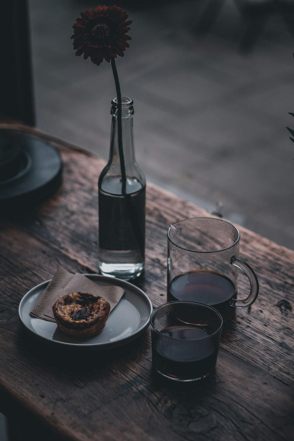 clear glass bottle beside clear drinking glass on brown wooden table