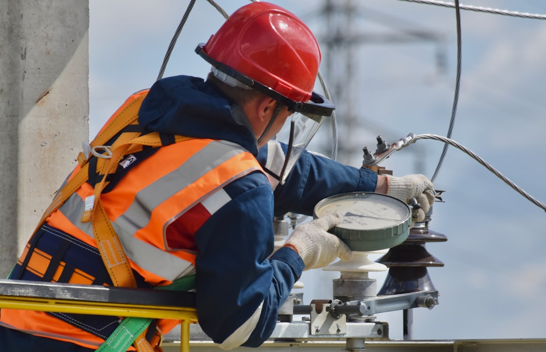 man in blue orange and white jacket wearing red helmet, The maintenance of transmission lines
