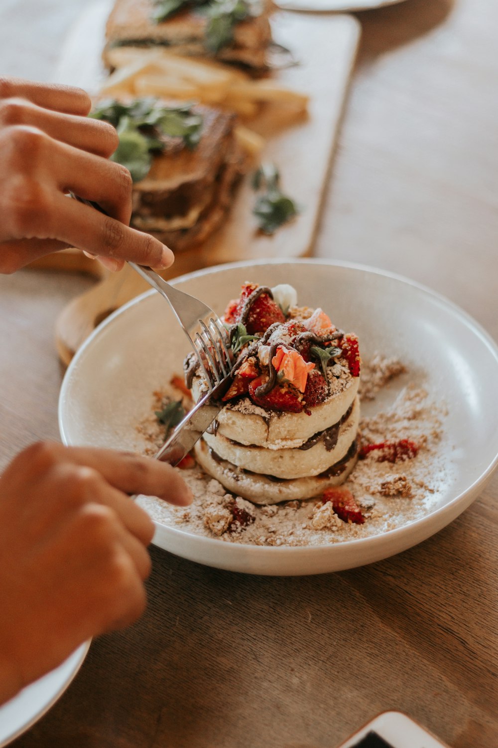 person holding stainless steel fork with white cream and strawberry on top