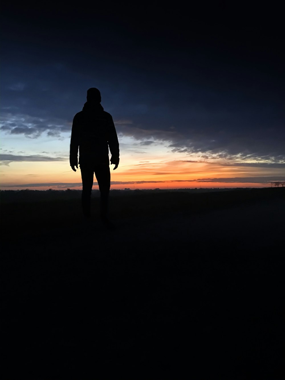 silhouette of person standing on seashore during sunset