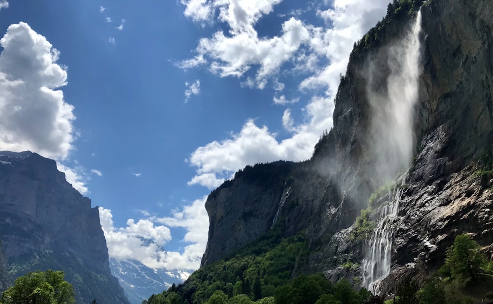 昼間の青空と白い雲の下に緑と灰色の山