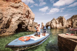 2 men riding on blue and white boat on body of water during daytime