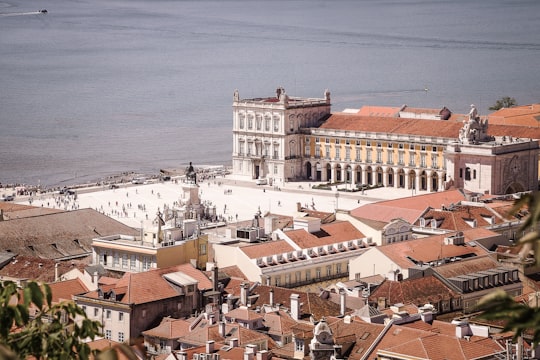 white and brown concrete buildings near body of water during daytime in Praça do Comércio Portugal