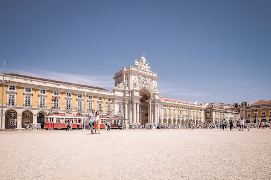 people walking on white sand near white concrete building during daytime in Praça do Comércio Portugal