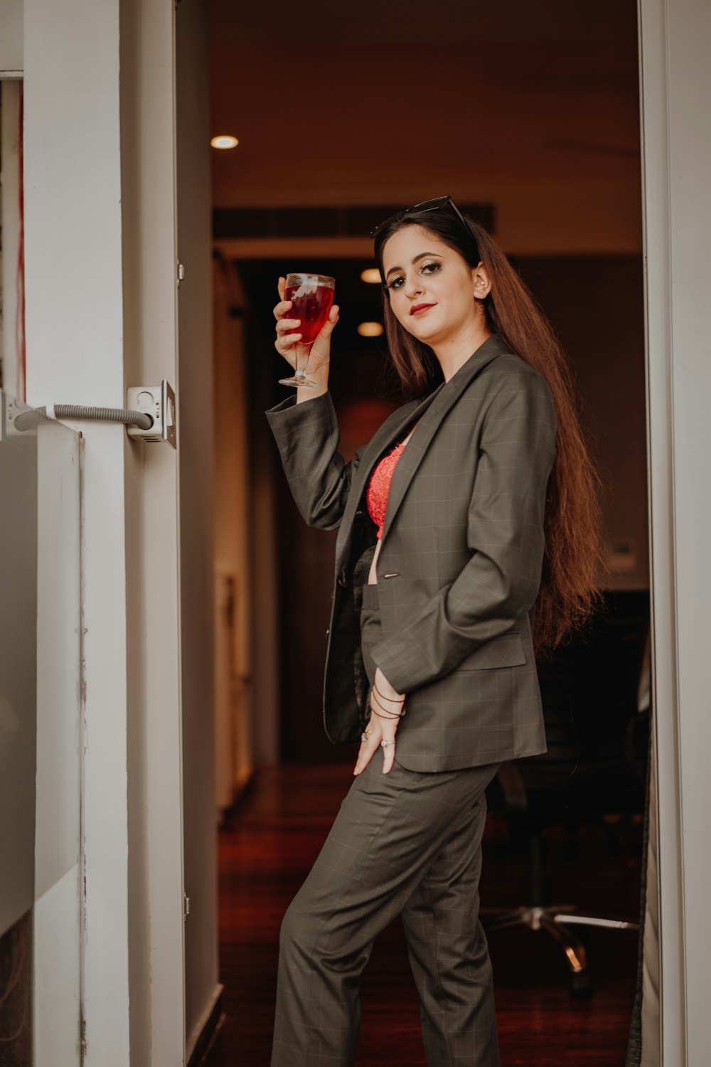 woman in black blazer and gray dress standing beside white wooden door