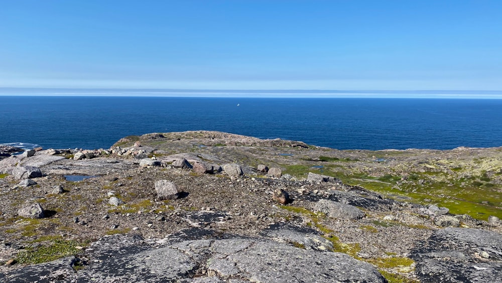 gray rocky mountain beside blue sea under blue sky during daytime