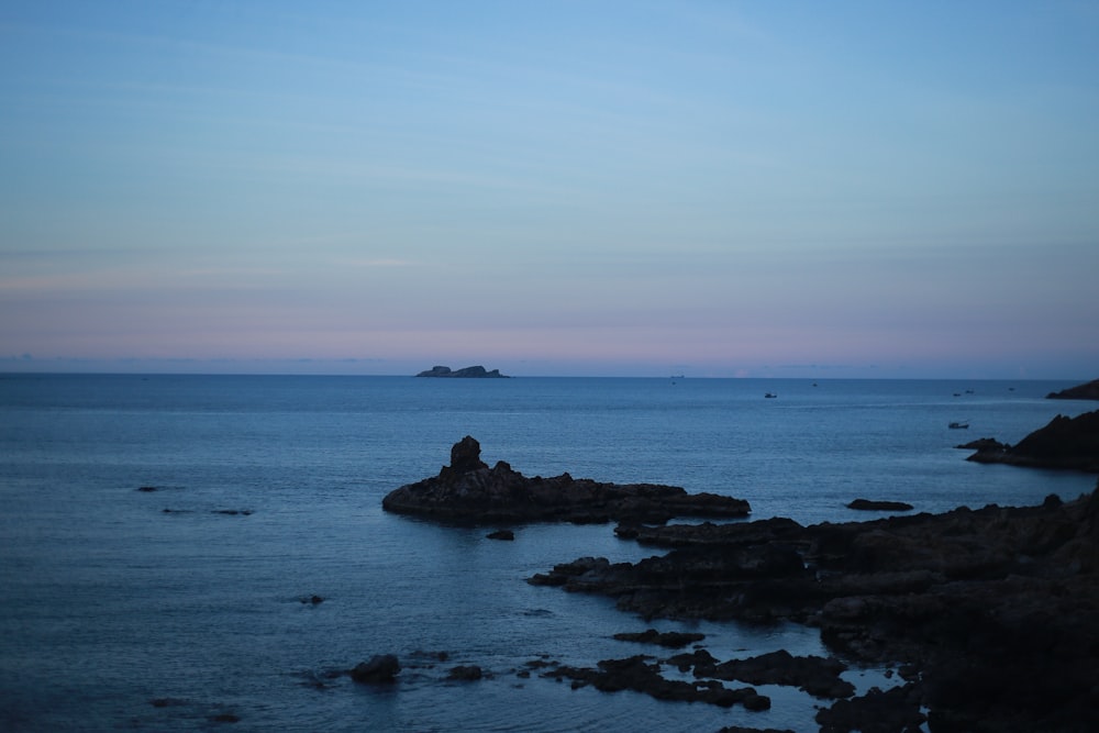 brown rock formation on sea under blue sky during daytime