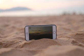 A close-up of a hand inserting an eSIM card into a sleek modern smartphone against a backdrop of a tropical beach.