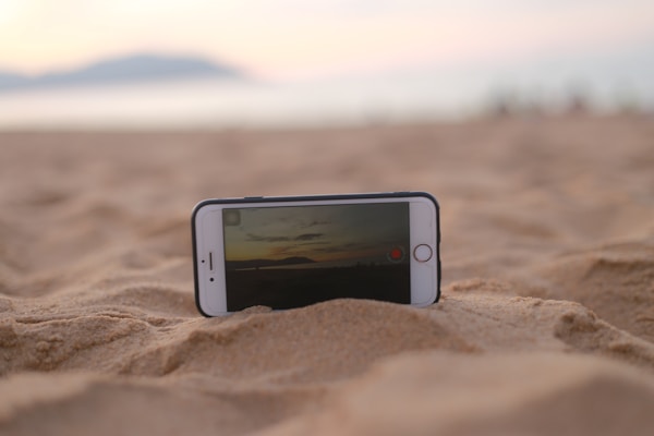 A close-up of a hand inserting an eSIM card into a sleek modern smartphone against a backdrop of a tropical beach.