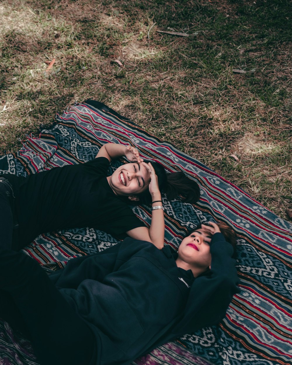 woman in black long sleeve shirt lying on red and white textile