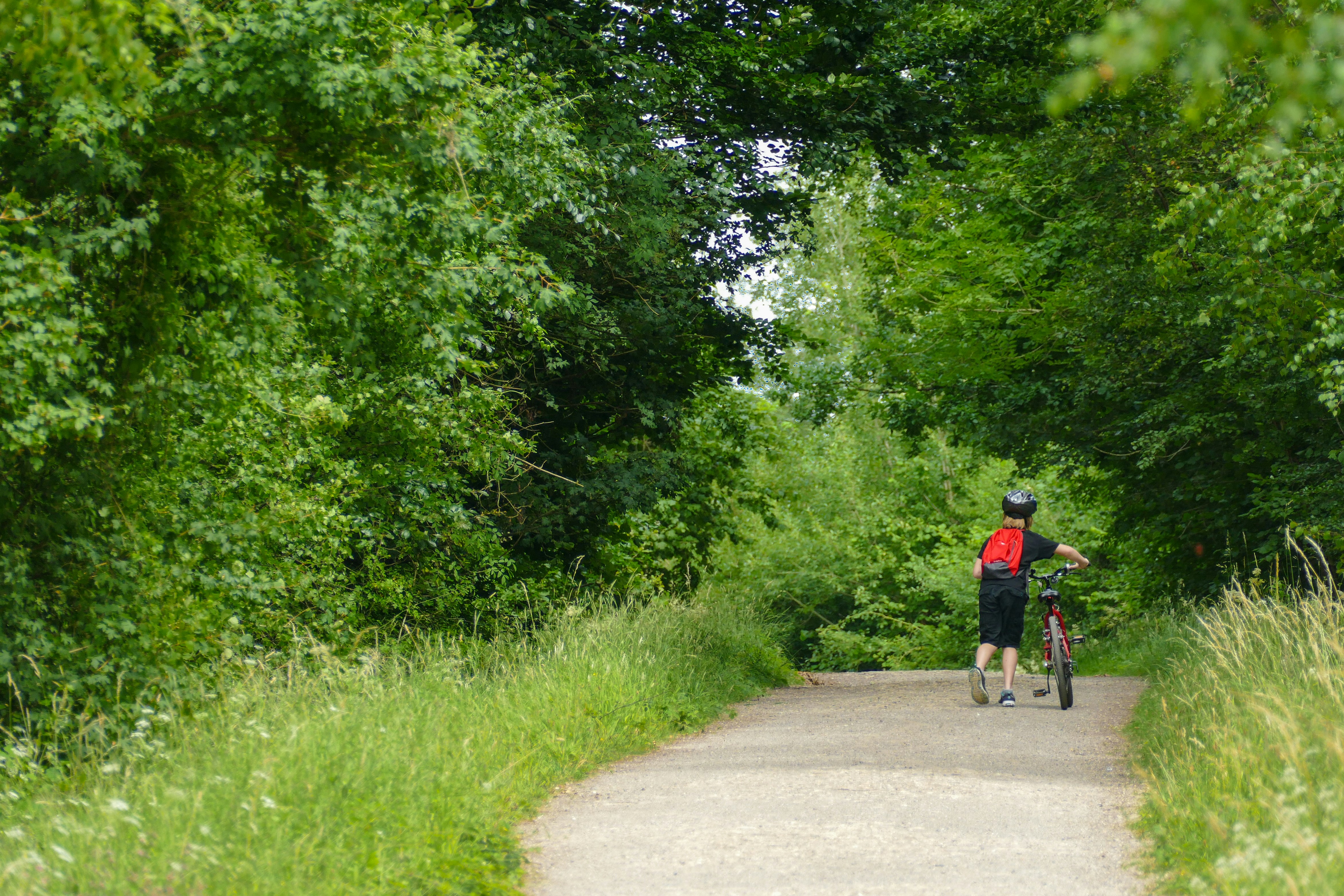 man in red jacket riding bicycle on road during daytime