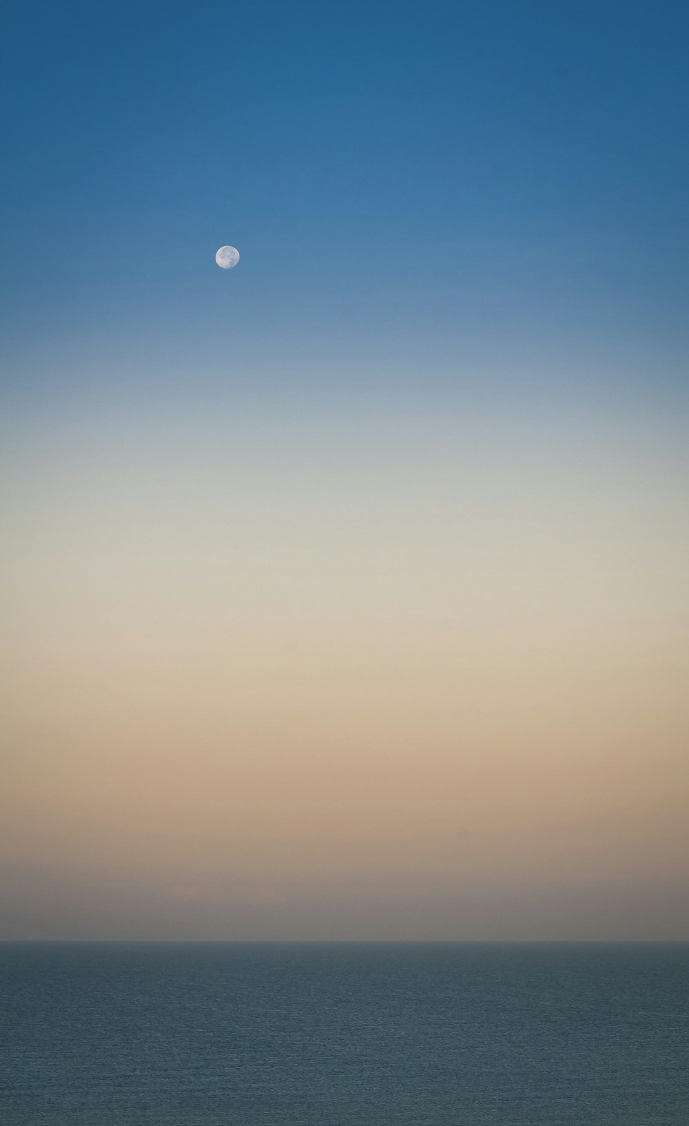 a view of the ocean with the moon in the sky