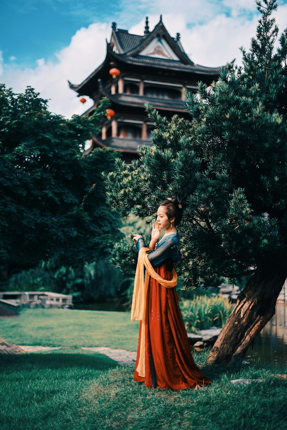 Mujer con vestido naranja de pie cerca de la casa de madera marrón durante el día