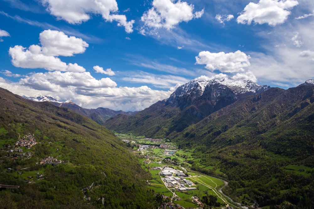 green grass field and mountains under blue sky during daytime