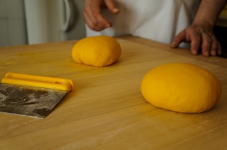 A premium stainless steel dough scraper resting on a wooden countertop.