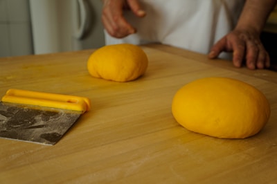 A premium stainless steel dough scraper resting on a wooden countertop.