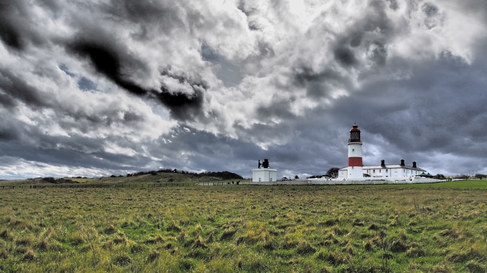 white and red lighthouse under gray clouds