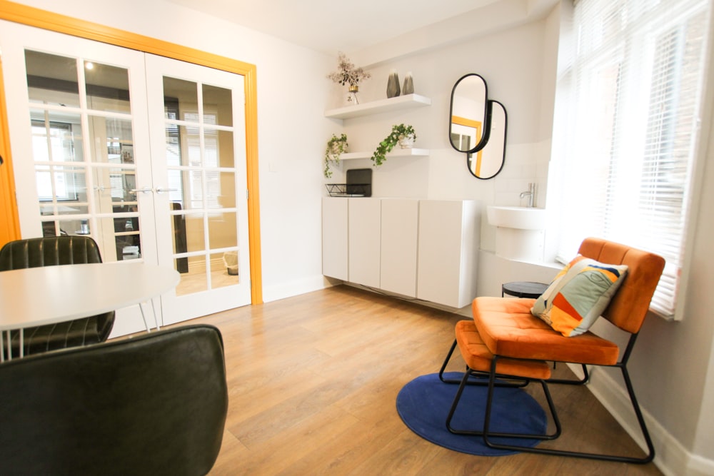 brown wooden framed black padded armchair beside white wooden cabinet