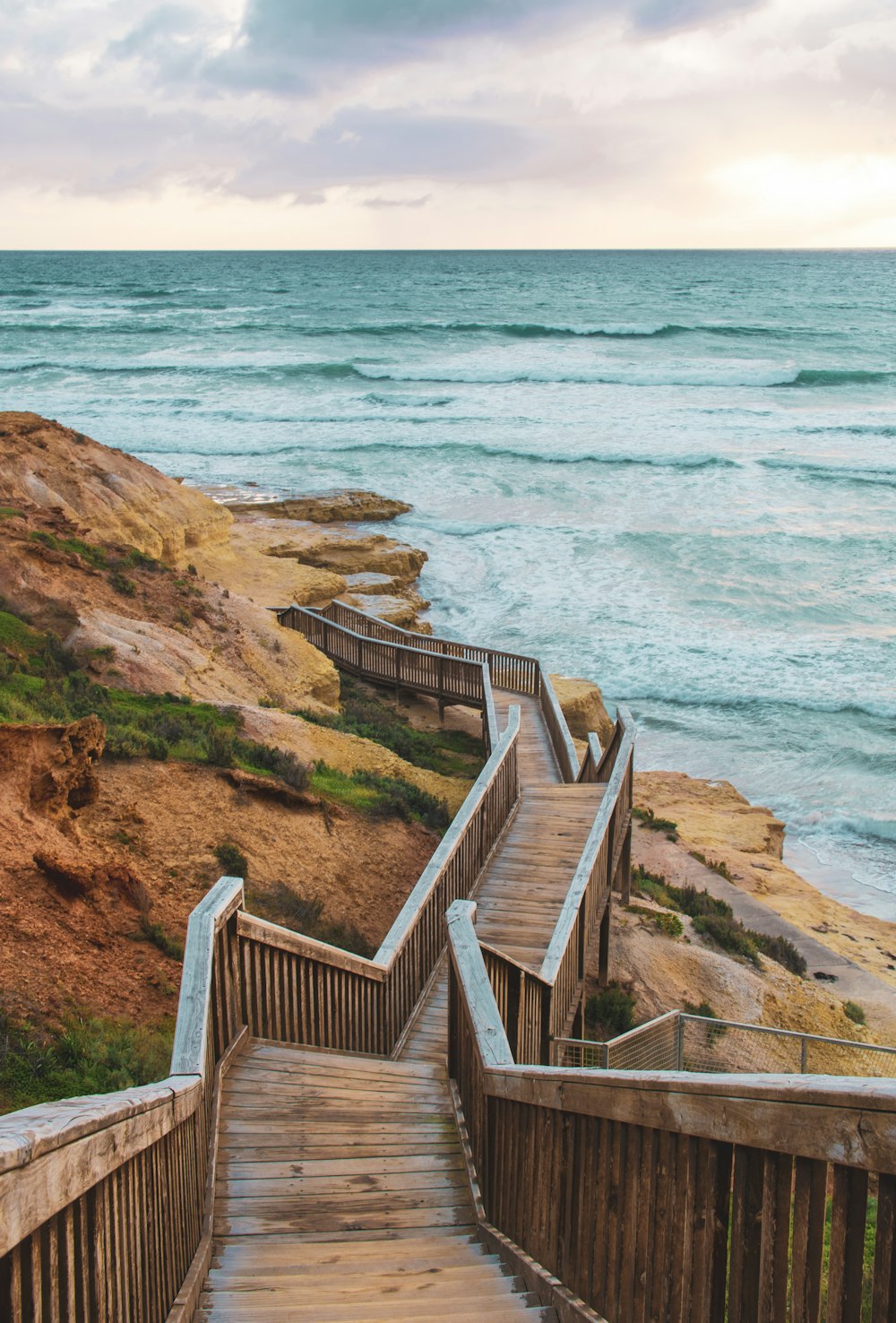 brown wooden stairs on brown rocky mountain near body of water during daytime