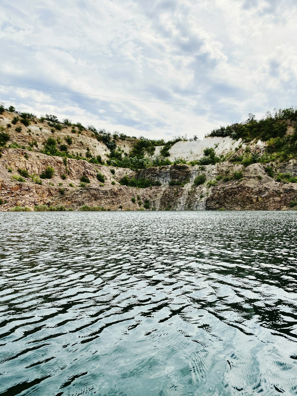 Plan d’eau près des arbres verts et de la montagne sous les nuages blancs et le ciel bleu pendant la journée