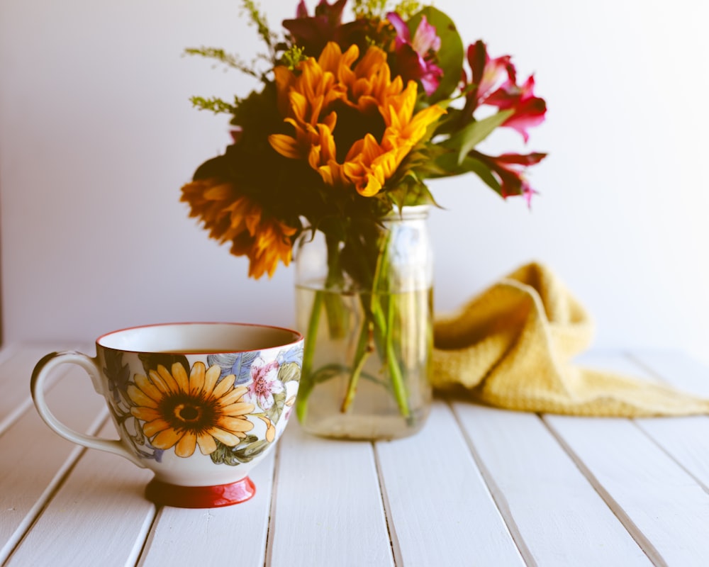 Gelbe und rote Blumen in klarer Glasvase