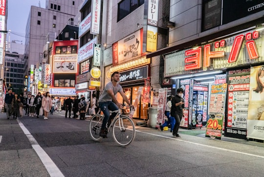 man in black t-shirt riding bicycle on road during daytime in Shibuya Japan